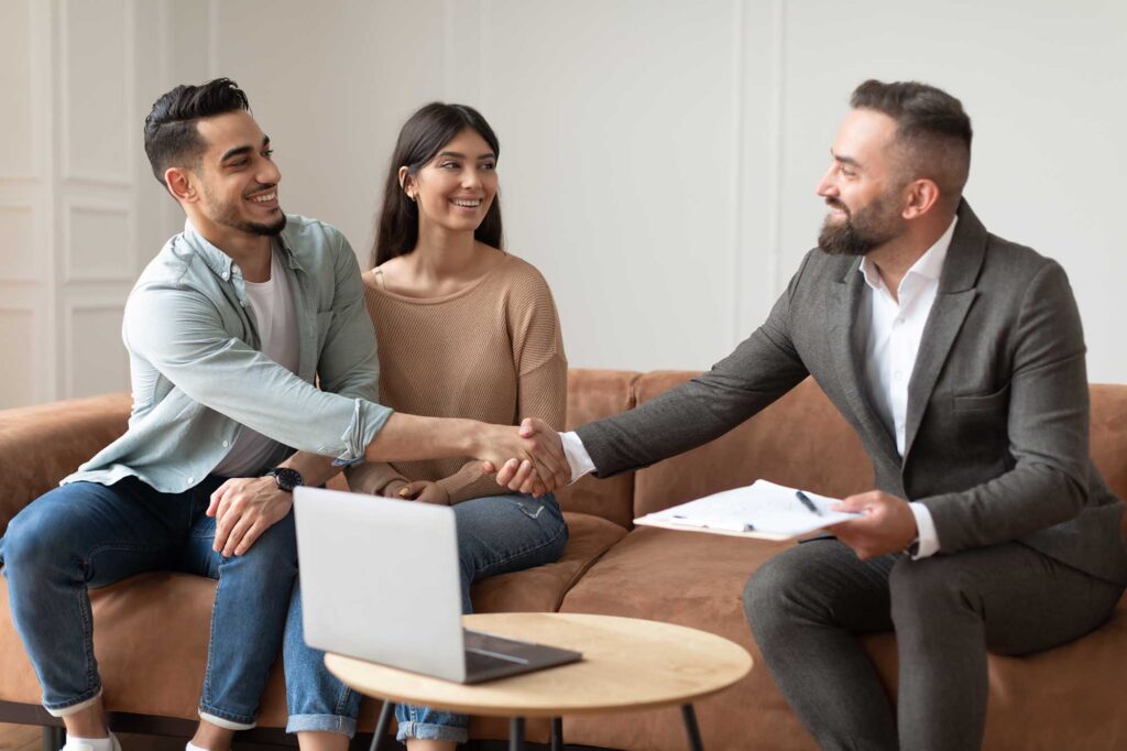 Millennial Couple Buying New home Shaking Hands With Realtor